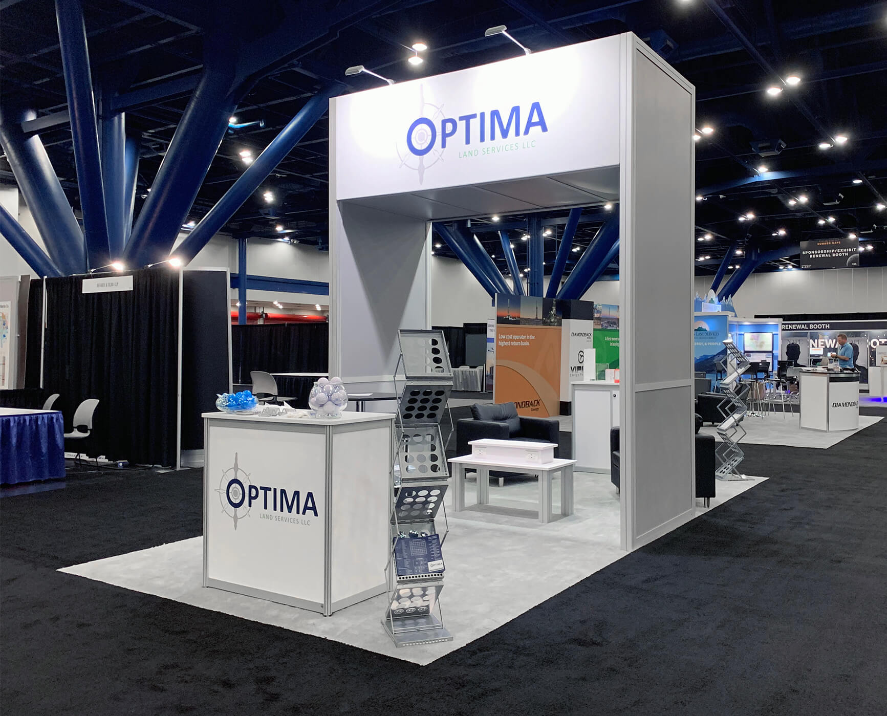 Logo on lit podium with literature in front of a cobranded booth with tall, middle divider and a cell phone charging station