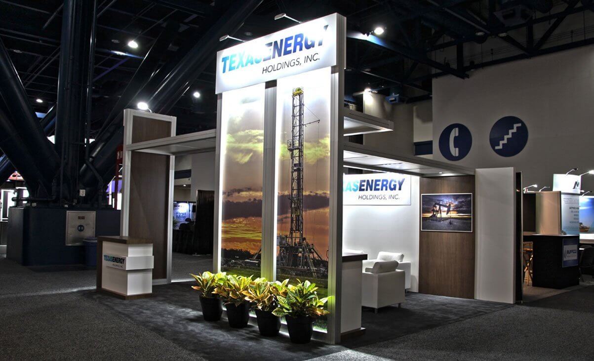 Custom exhibit with a modern look, seating, and graphic panels with monitors on the back wall; can be configured as an island