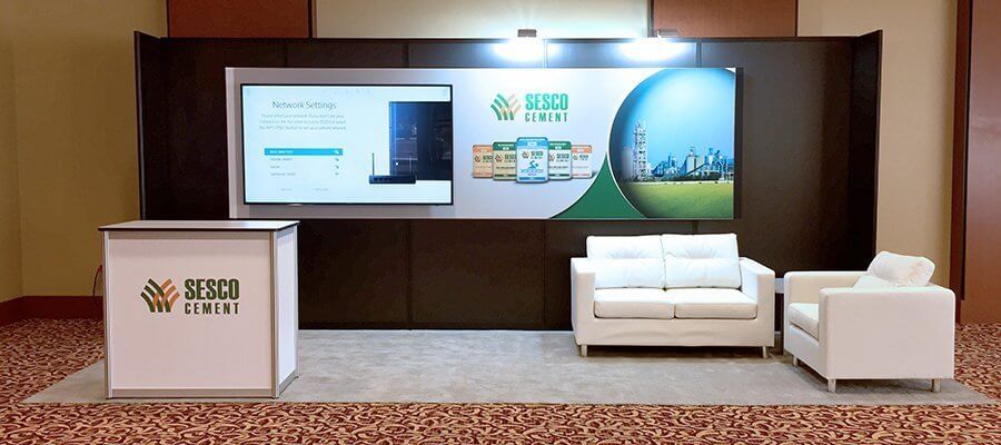 7 x 19 inline booth with top-lit signage, monitors, seating area, and podium from Exhibit Network’s modular rental inventory