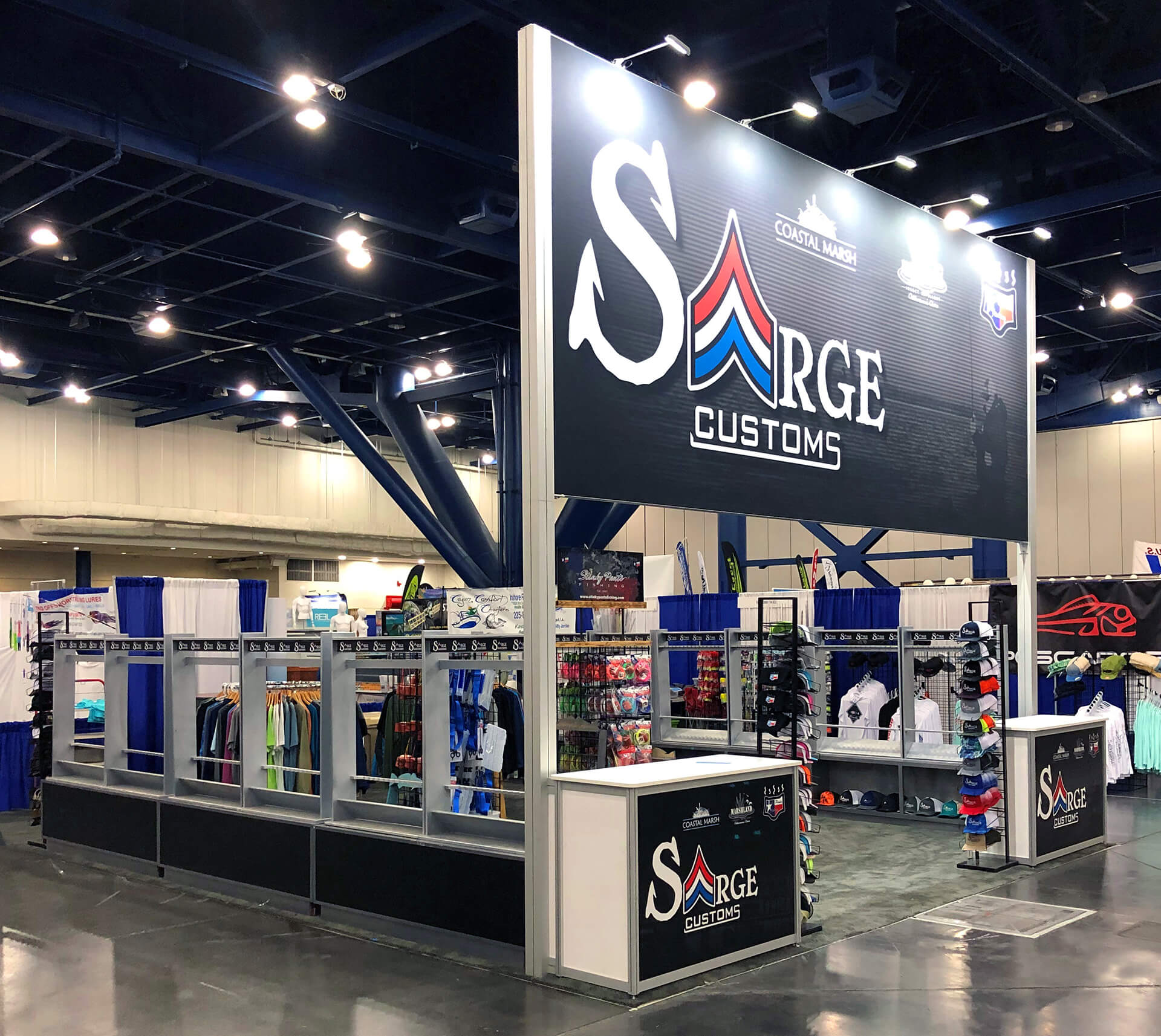 Well-lit, branded signage for Sarge Customs exhibit with product displays, trade show personnel, and purchase options.