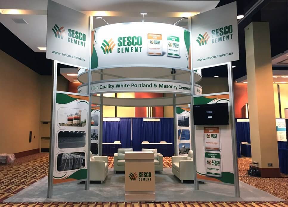 Large modular island booth with top-lit signage, graphic walls, monitors, and seating from Exhibit Network’s rental inventory
