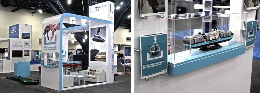 Trade show booth feat. conference area with two couches, tall towers for visibility, video monitors, and a lit display case.