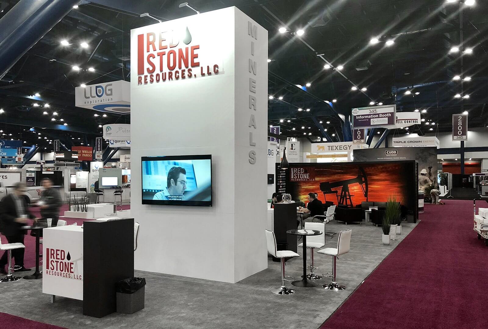 Tower structure with large-format graphics and video monitors offers clear visibility to an island exhibit and hospitality.