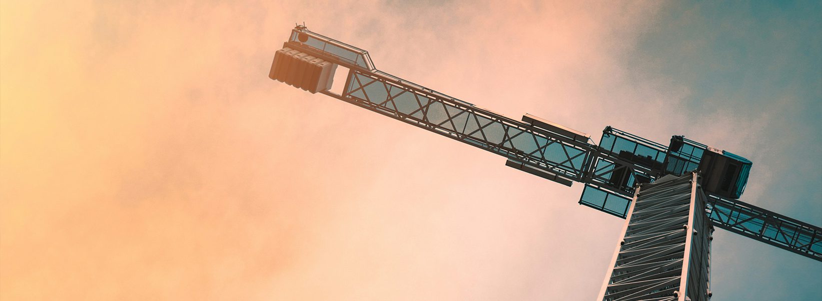 A steel crane towers over a construction site with a pale, cloudy yellow and blue sky representing how Exhibit Network enables success at expos like CONEXPO CON/AGG, World of Concrete and Utility Expo