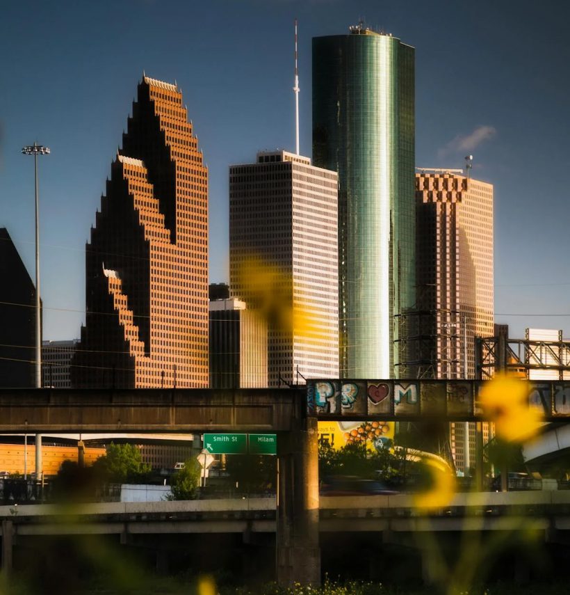 Shiny silver, red, and tan skyscrapers with a deep blue Texas sky represent Exhibit Network roots serving the Houston exhibit and convention center industry including energy, oil, and gas trade shows
